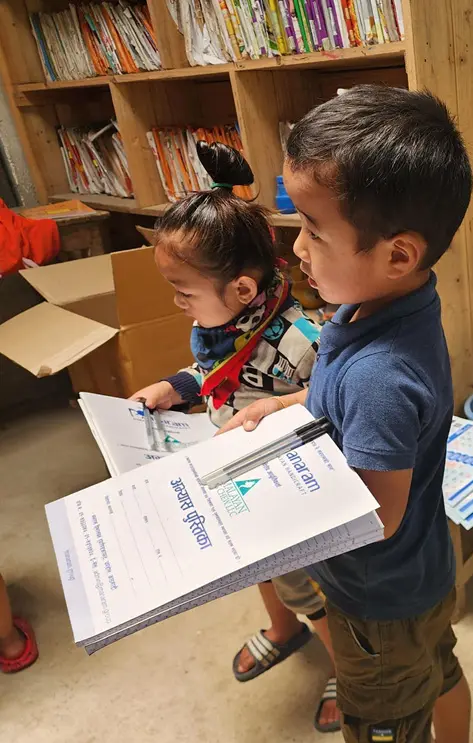 A young boy holding an exercise book in a Manaram library