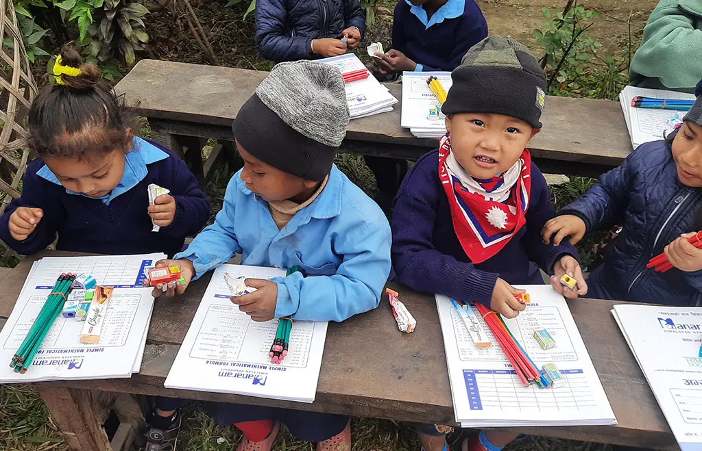 Young students in woollen caps working with new stationery at their desks