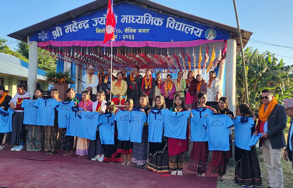 Students holding up new blue uniforms outside Shree Mahendra Jyoti Secondary School